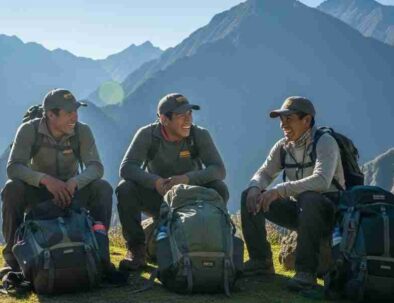 A group of smiling, well-equipped porters resting on a sunny mountain pass, an example of ethical and sustainable tourism in Peru.