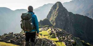 A thoughtful traveler looking out at the misty sunrise over Machu Picchu, representing the profound personal journey that contrasts with Peru travel expectations vs reality.