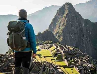 A thoughtful traveler looking out at the misty sunrise over Machu Picchu, representing the profound personal journey that contrasts with Peru travel expectations vs reality.