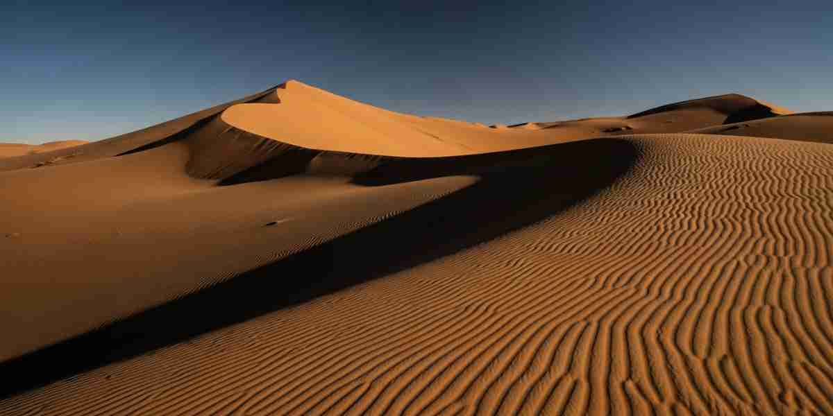 The vast, empty landscape of the Nazca desert embodies Peruvian desert solitude, with wind-sculpted sand dunes stretching to the horizon under a clear blue sky.