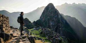A lone hiker pausing on a high Andean pass during a transformative travel in Peru experience, looking out at a vast, sunlit mountain range, embodying a moment of deep reflection.